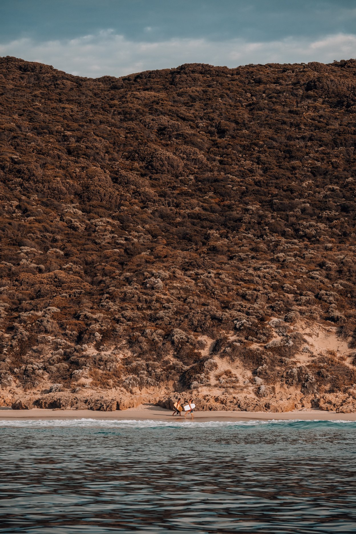 People Walking on a Beach Holding Surfboards 